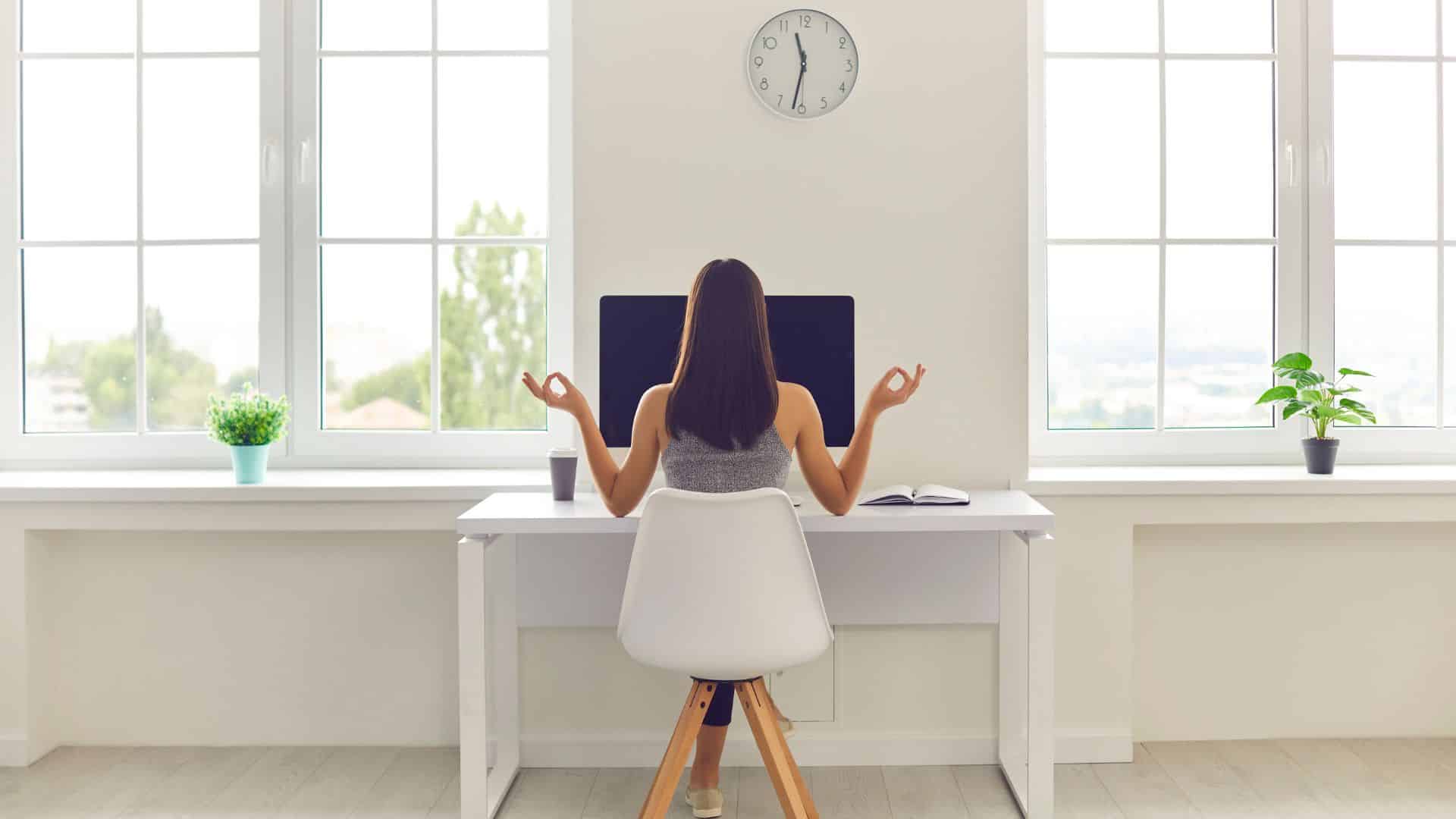 Naine istmas arvuti taga seljaga meie suunas, käed zen asendis