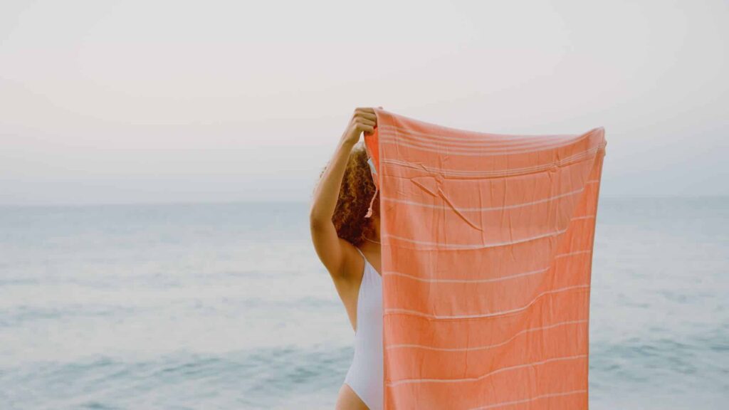 Naine hoiab mererannas rannalinna enda näo ees