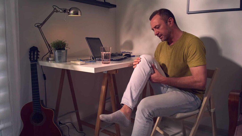 Liigesed. Artroveron-Mees kirjutaslaua taga hoiab haigest põövest kinni