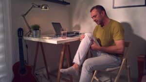 Liigesed. Artroveron-Mees kirjutaslaua taga hoiab haigest põövest kinni