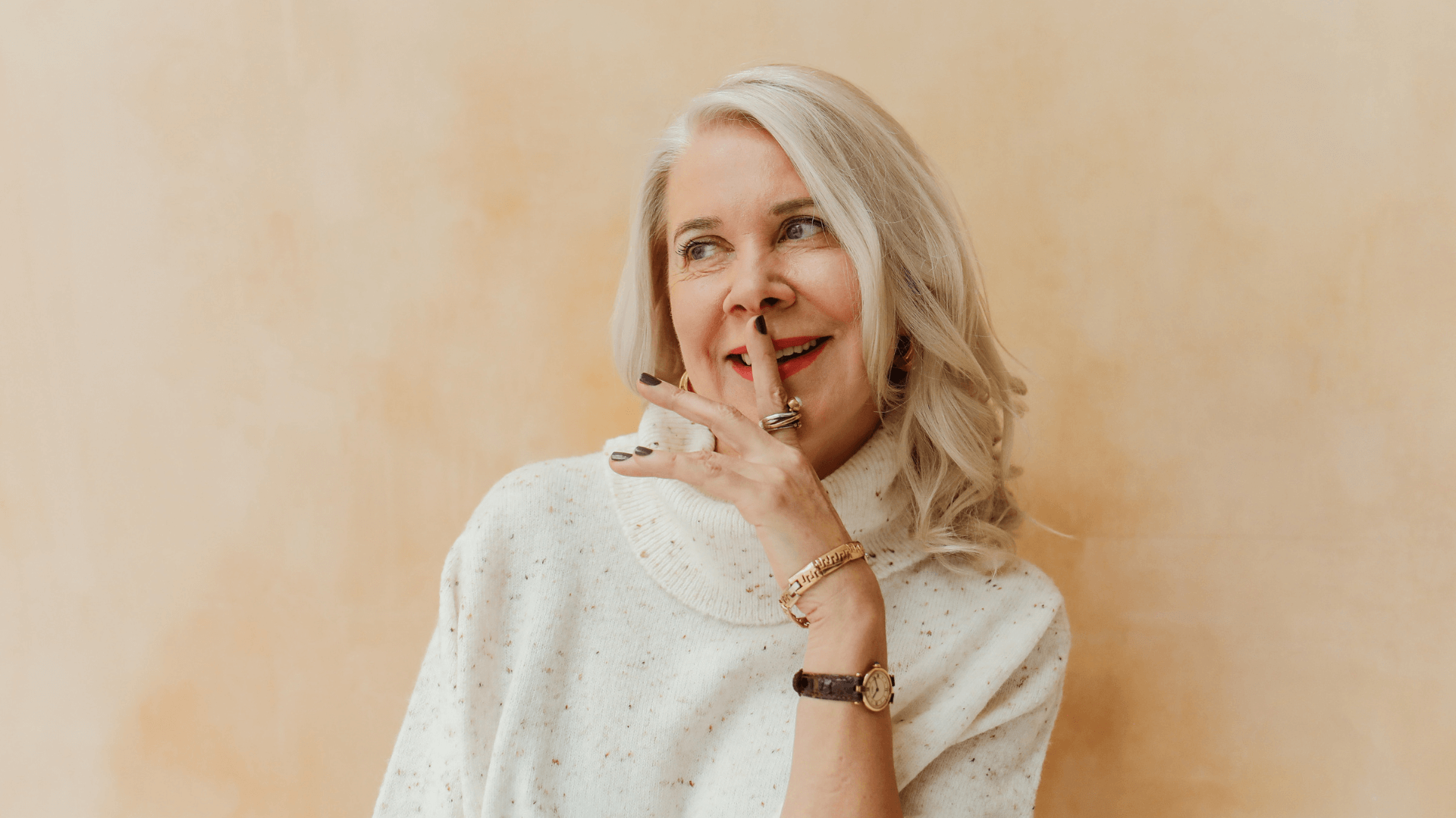 Kollageen, keskealine naine, sõrm huultel ja naeratab